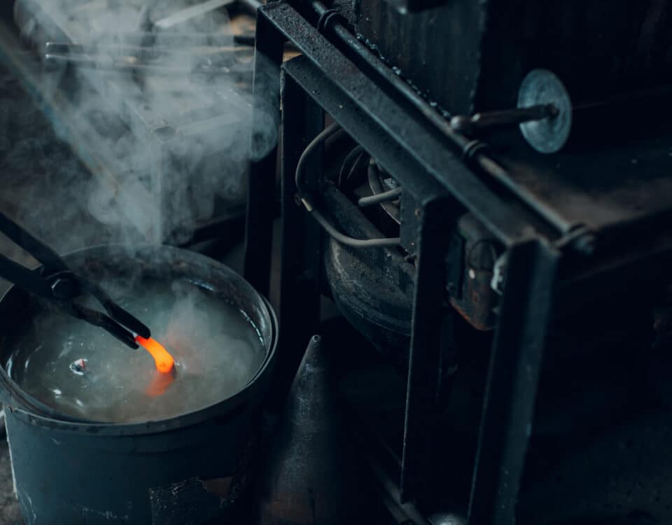 Blacksmith forges and tempering metal horseshoe in jar with water at forge
